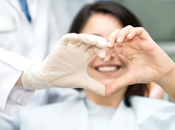 Dentist and patient making heart symbol with their hands